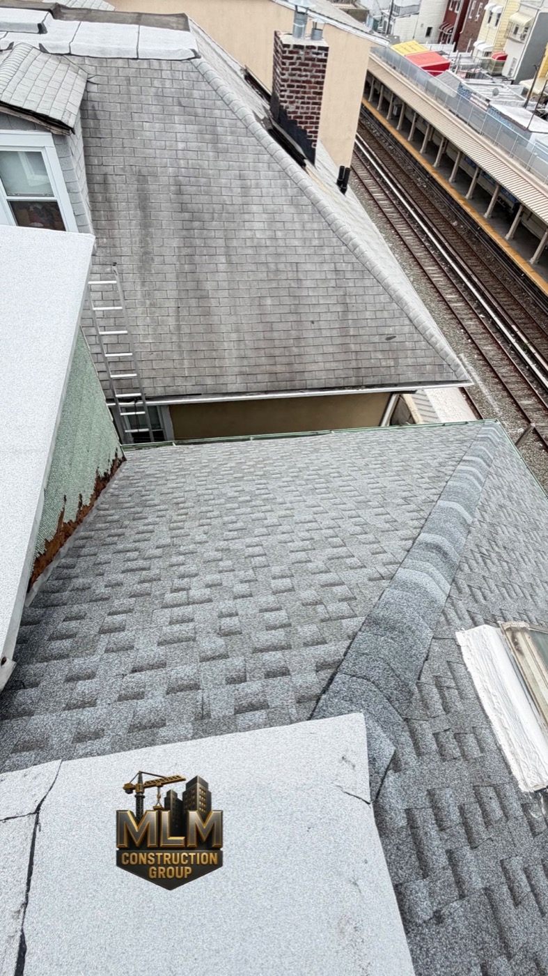 Attached Brooklyn row house roofs meeting at shared party walls beside an elevated train line
