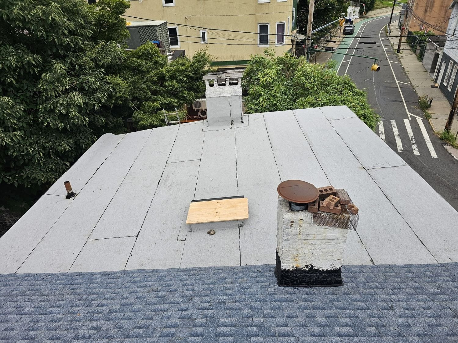 Brooklyn roof where a shingle slope meets a flat roof at a rebuilt chimney