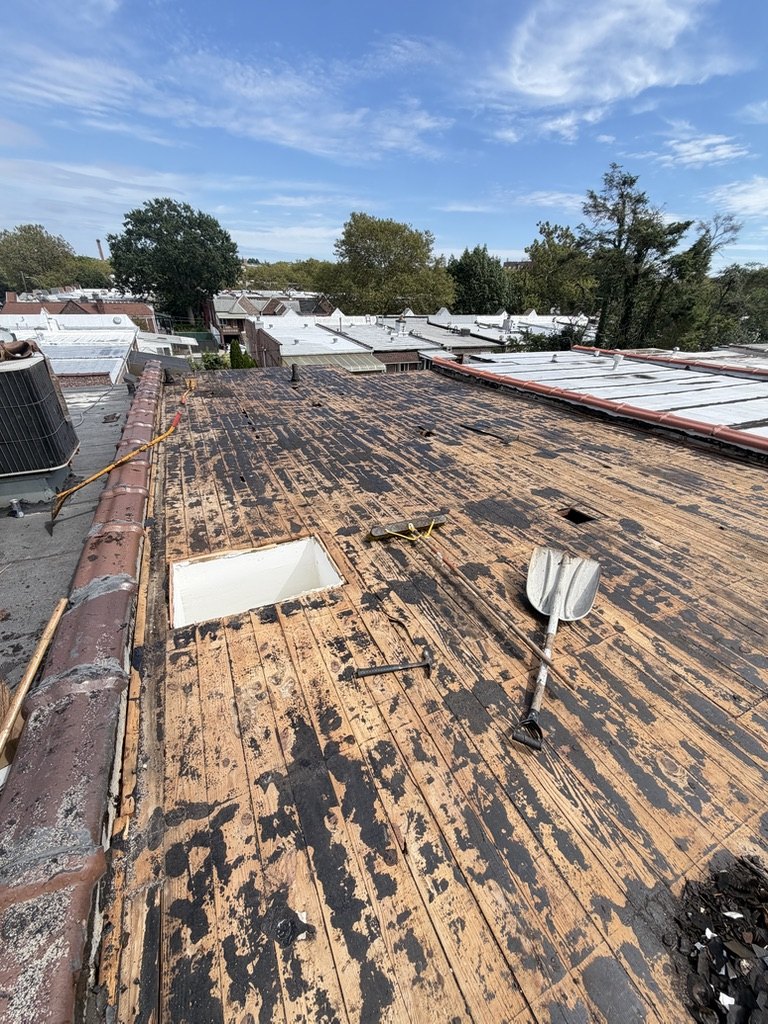 Brooklyn flat roof stripped to the original plank deck with old bitumen still stuck to the boards